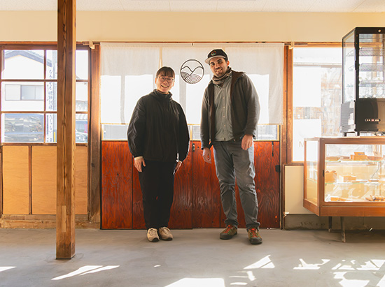 [写真]お店入口前にて、店主の田中さんご夫妻。